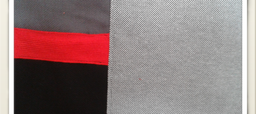 Loneta grisa eta beltza, karratu txiki eta tira gorriarekin.